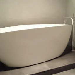 Wolnostojąca wanna w łazience po remoncie, z nowoczesną armaturą, Piastów. Minimalistyczny design i szara kolorystyka ścian tworzą spójną całość.