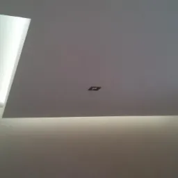 Nowoczesny sufit podwieszany z oświetleniem LED, dwa kwadratowe punkty świetlne. Minimalistyczne wykończenie wnętrza w jasnych barwach.