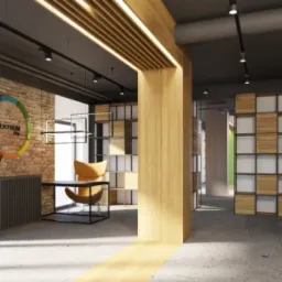 Wnętrze biura z ceglaną ścianą, logo firmy, biurkiem z krzesłem i regałami w tle, oświetlone punktowymi lampami sufitowymi i listwami LED.