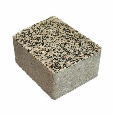 Pojedyncza kostka brukowa o szarej, porowatej fakturze z wierzchem pokrytym drobnymi, czarno-białymi kamyczkami na białym tle.