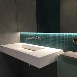 REM-BUDD Piotr Czachowski - Nowoczesna, prostokątna umywalka nablatowa z chromowaną baterią, podświetlona od dołu zielonymi mozaikowymi płytkami, widoczne przygotowania do montażu gniazdka elektrycznego.
