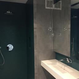 REM-BUDD Piotr Czachowski - Nowoczesna łazienka z ciemnozieloną mozaiką pod prysznicem, szarą płytą wielkoformatową, wiszącą białą umywalką i designerskim oświetleniem w postaci szklanych kul na cienkich przewodach.