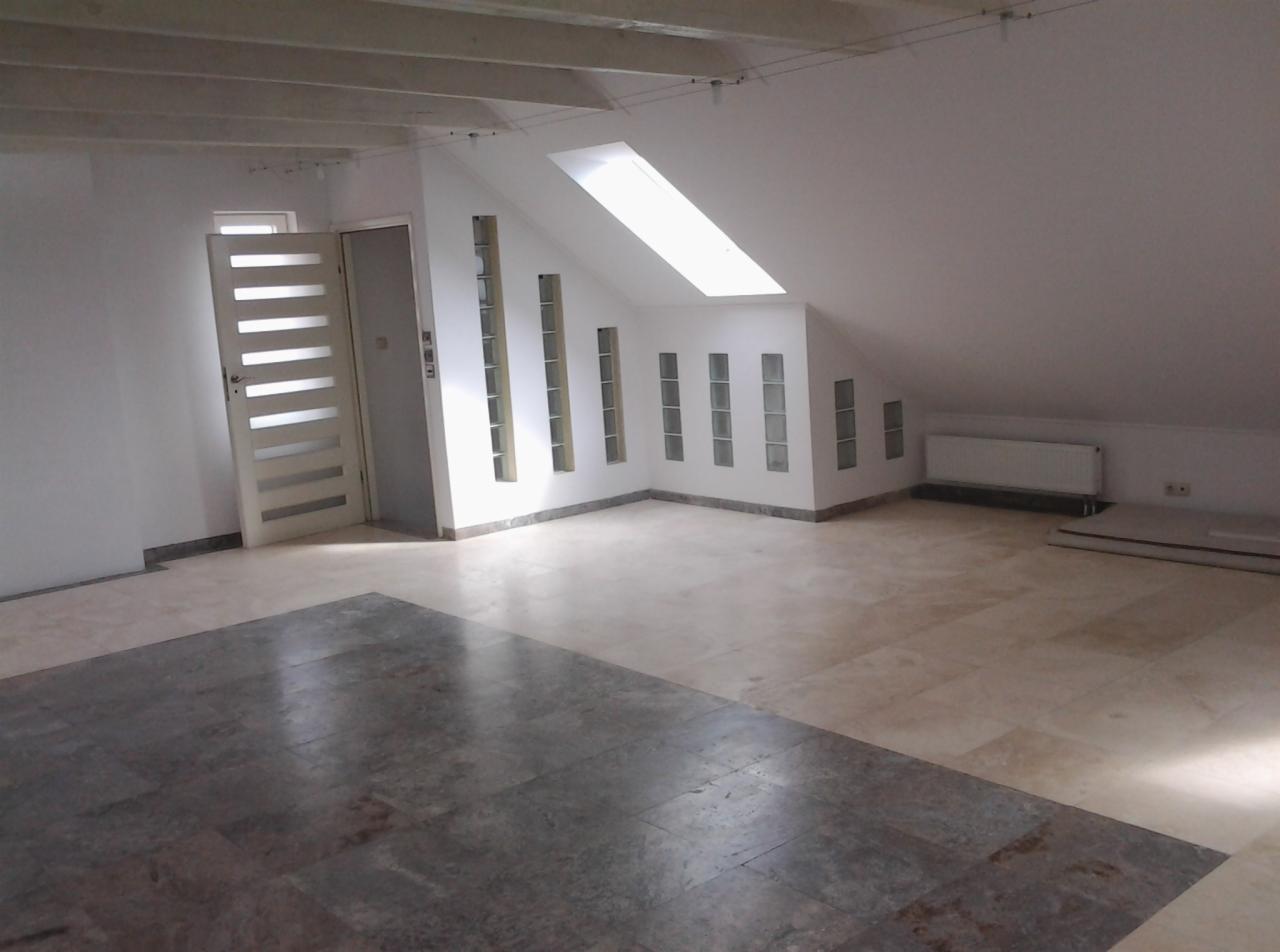 Poddasze po remoncie z nową podłogą z płytek w dwóch odcieniach, białą stolarką okienną z luksferami i białą, nowoczesną, przeszkloną, wewnętrzną stolarką drzwiową.