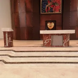 Marmurowe schody prowadzące do ołtarza z marmurowym blatem i podstawą, w tle drewniana ściana z obrazem religijnym i złotym sercem.