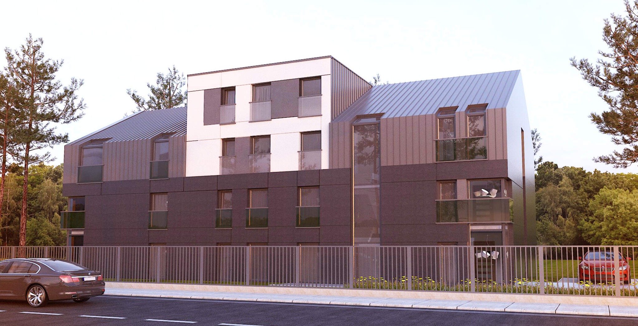 Wizualizacja budynku wielorodzinnego z metalową elewacją w odcieniach szarości i bieli, z balkonami i skośnym dachem, otoczonego zielenią i ogrodzeniem, z widocznymi samochodami na ulicy.