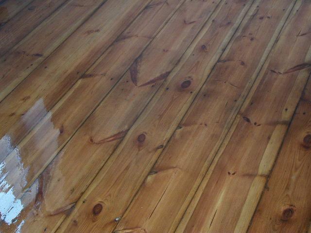 Świeżo polakierowana podłoga z desek sosnowych, widoczne odbicie światła na mokrej powierzchni.