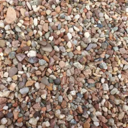 Mieszanka drobnego, kolorowego kruszywa o zaokrąglonych krawędziach, dominują odcienie beżu, brązu, szarości i bieli, tworząc naturalną mozaikę.