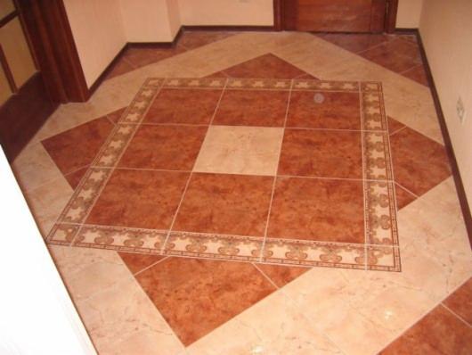 Ukończona podłoga z płytek ceramicznych w odcieniach beżu i terakoty, ułożona we wzór kwadratu w kwadracie z dekoracyjnym obramowaniem.