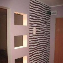 Nowoczesna aranżacja przedpokoju: ściana z motywem zebry, wnęki z oświetleniem i minimalistyczny design, podkreślony przez jasne kolory i proste linie.