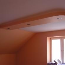 Wykończenie poddasza: pomarańczowe ściany, okno, sufit z wnęką i halogenami. Ukończony remont wnętrza.