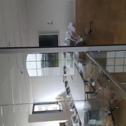 Nowoczesne biuro z przeszkloną ścianą działową, widoczne biurka i krzesła w folii ochronnej, drewniana podłoga i sufit z perforacją.