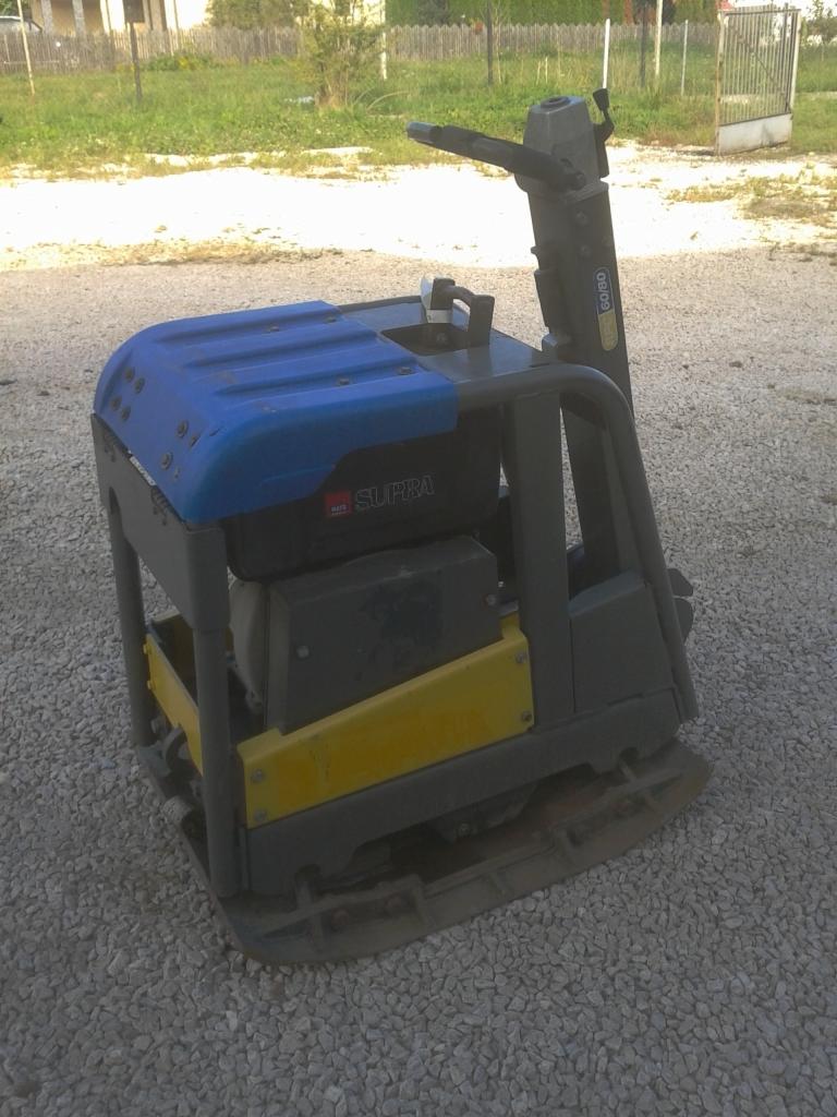 Używana zagęszczarka gruntu Belle Supra 500kg na żwirowym podłożu, widoczne ślady użytkowania i zabrudzenia.