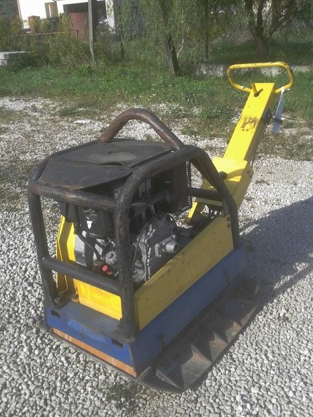 Używana zagęszczarka gruntu Dynapac, model 480 kg, z widocznymi śladami użytkowania, stoi na żwirowym podłożu, z elementami żółtej i niebieskiej farby.