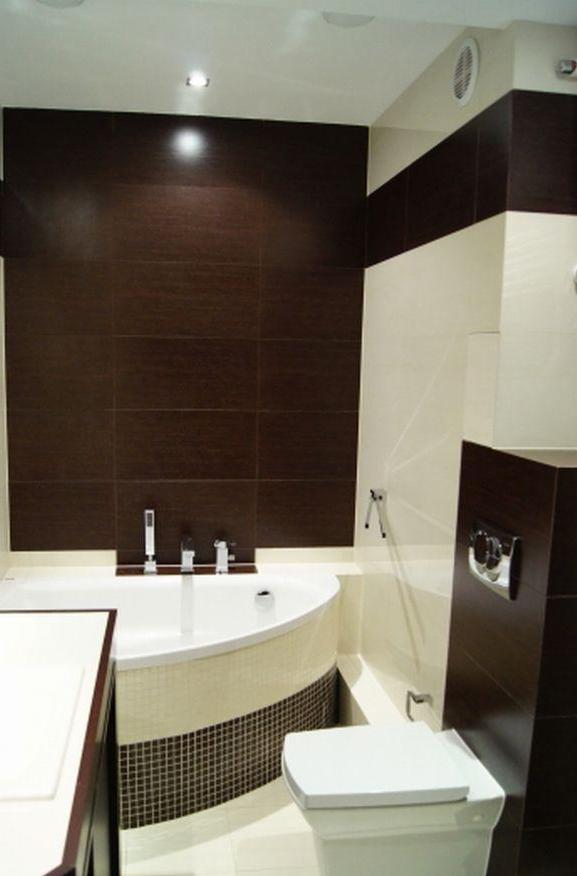 Nowoczesna łazienka z wanną narożną obłożoną mozaiką, brązowymi płytkami imitującymi drewno na ścianie i podwieszaną toaletą.