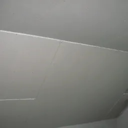 Płyty gipsowo-kartonowe zamontowane na poddaszu, widoczne łączenia płyt i elementy instalacji wentylacyjnej.