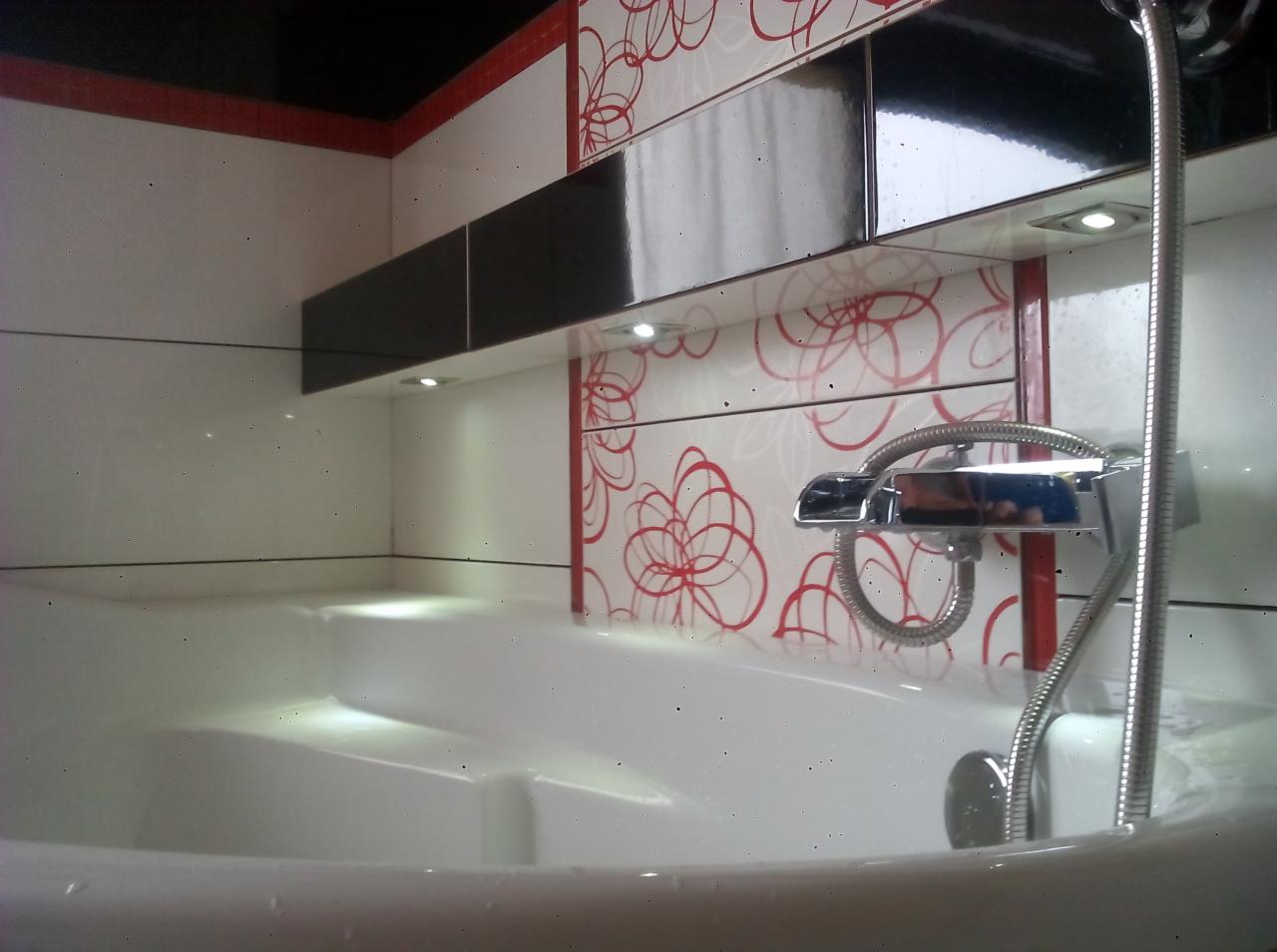 Nowoczesna łazienka z białą wanną, chromowaną armaturą i płytkami w geometryczne wzory. Oświetlenie punktowe podkreśla minimalistyczny design.