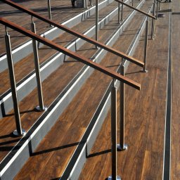 Opiela-parkiety.pl - Nowoczesne schody z drewnianymi stopniami i metalowymi barierkami. Widoczne detale wykończenia i precyzja wykonania. Schody na zewnątrz budynku.