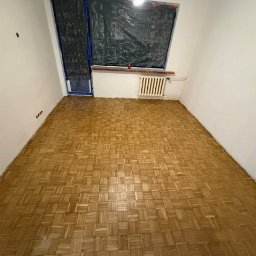 Opiela-parkiety.pl - Parkiet po cyklinowaniu w pokoju z grzejnikiem i zabezpieczonym oknem. Widoczne ślady po cyklinowaniu, podkreślające odnowiony wygląd podłogi.