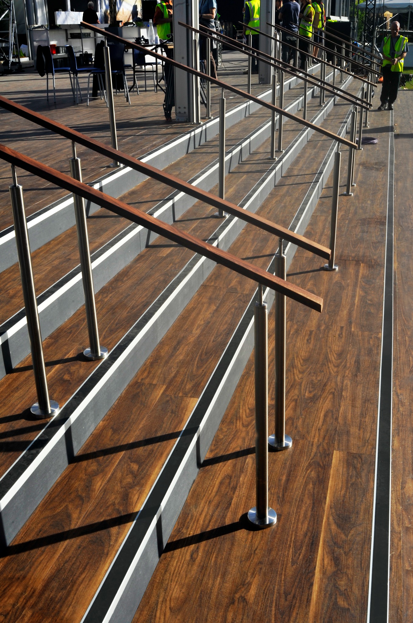 Nowoczesne schody z drewnianymi stopniami i metalowymi barierkami. Widoczne detale wykończenia i precyzja wykonania. Schody na zewnątrz budynku.