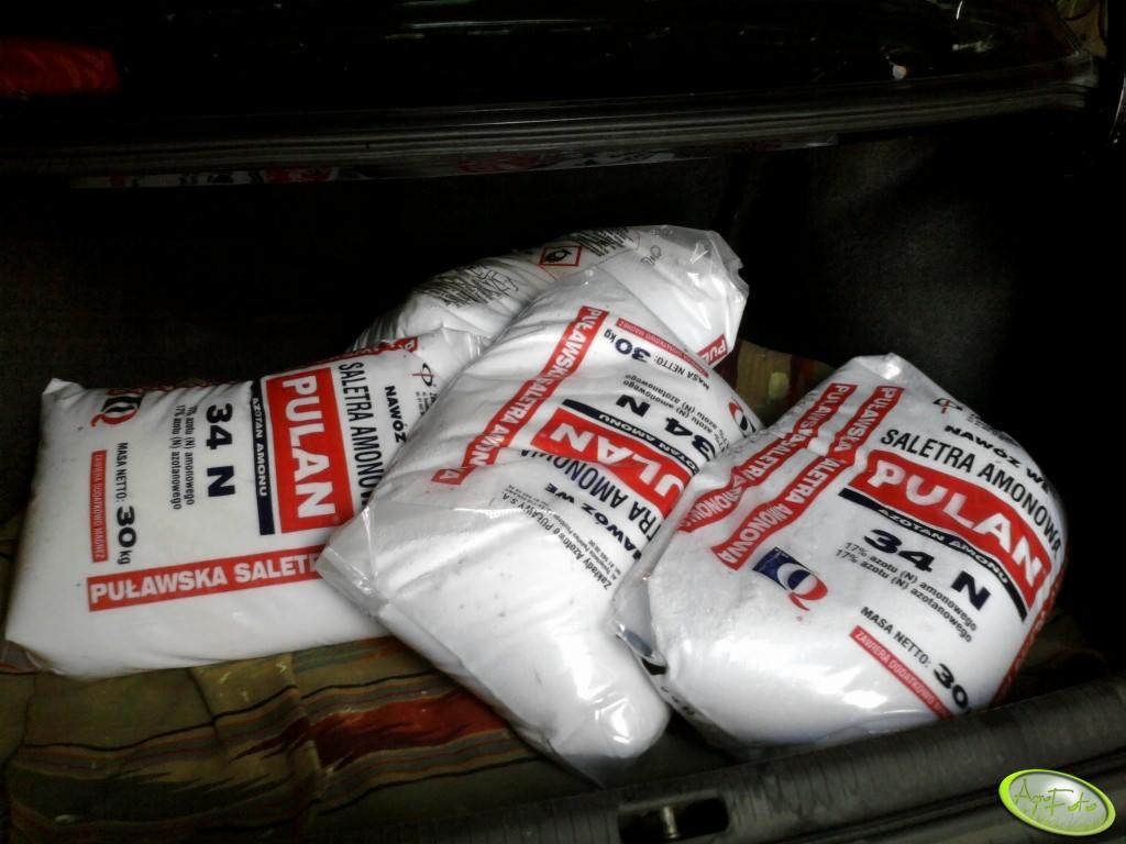 Kilka worków saletry amonowej marki Pulan 34 N w bagażniku samochodu na wzorzystej macie.