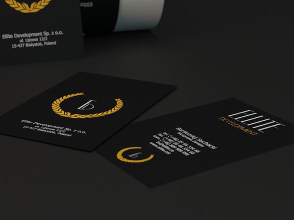 Eleganckie, czarne wizytówki z logo firmy otoczonym złotym wieńcem laurowym, prezentujące dane kontaktowe, leżące na ciemnym tle.