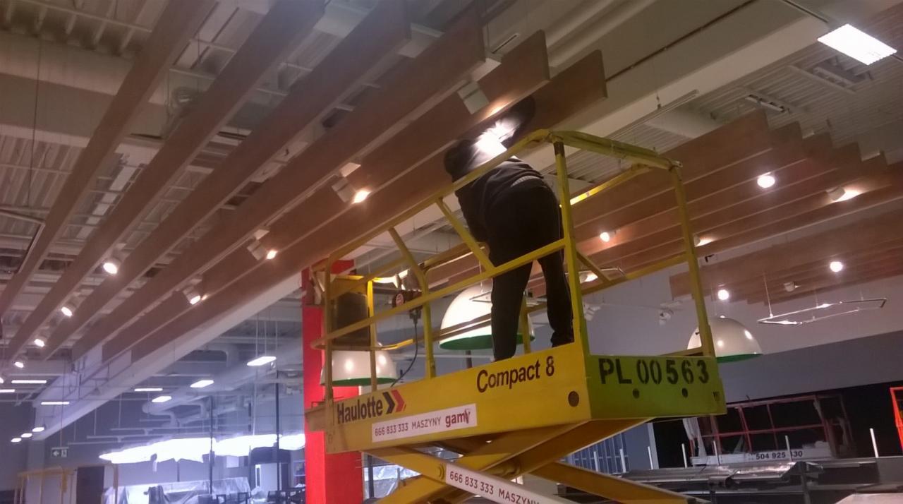 Montaż drewnianych paneli sufitowych w obiekcie handlowym z użyciem podnośnika Haulotte Compact 8.