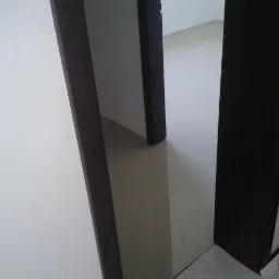 Beżowa, gładka podłoga w korytarzu z ciemnymi futrynami drzwi, widok z góry pod kątem.