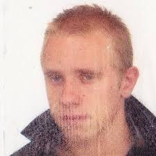 Portret mężczyzny z krótkimi blond włosami, lekko zarośniętego, na białym tle. Zdjęcie wykonane w Wałbrzychu.