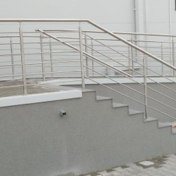 Dod-met - Zewnętrzne schody z szarą elewacją i balustradą ze stali nierdzewnej z poziomymi prętami, widok z boku.