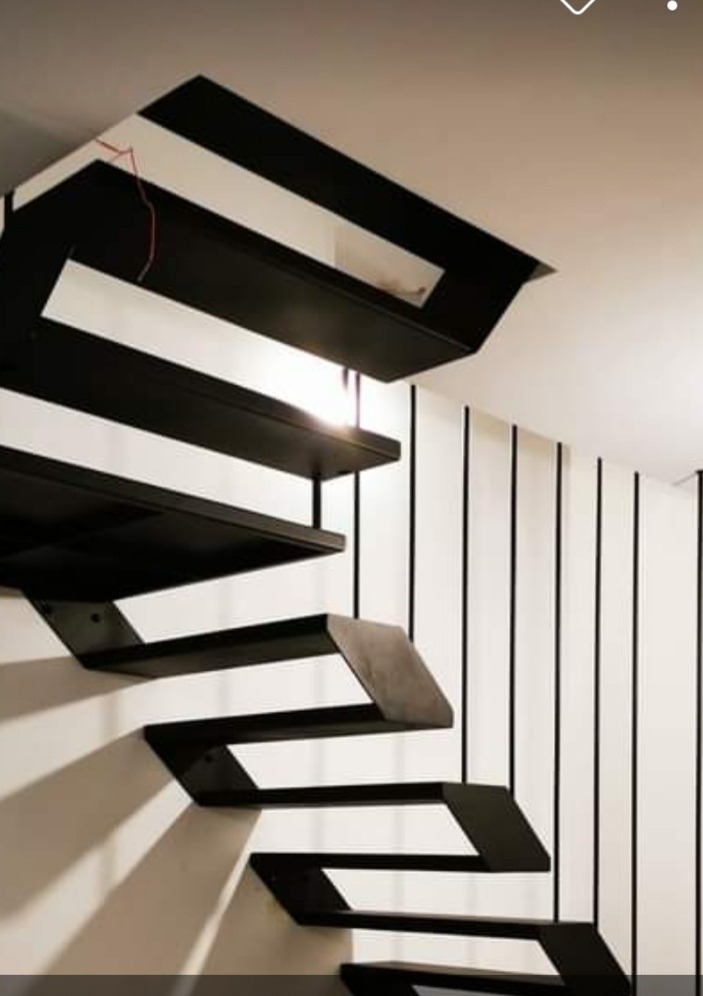 Nowoczesne schody wspornikowe z czarnego metalu, minimalistyczny design, biała ściana w czarne pionowe pasy, oświetlenie punktowe.