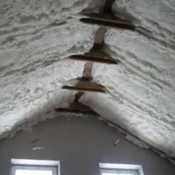 Izolacja poddasza pianką poliuretanową, widoczne drewniane elementy konstrukcyjne dachu