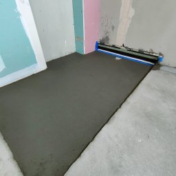 PPUH Art-Rad - Wylana, świeża wylewka podłogowa w pomieszczeniu z przygotowanymi ścianami do dalszych prac wykończeniowych. Widoczne profile przyścienne.