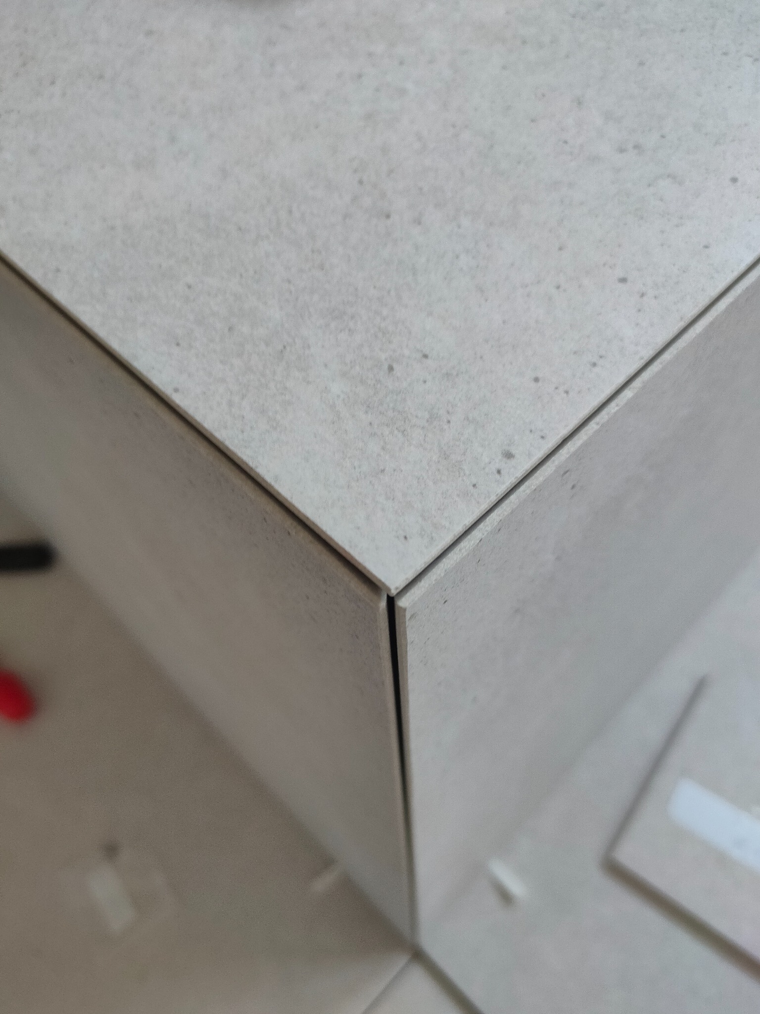 Precyzyjne połączenie płytek w narożniku, ukazujące dokładność wykonania i estetykę wykończenia. Jasne, matowe płytki tworzą minimalistyczny, nowoczesny wygląd.