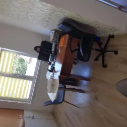 Osoba pracuje przy biurku z komputerem w jasnym biurze w Raniżowie, widok z boku na stanowisko pracy z oknem w tle.