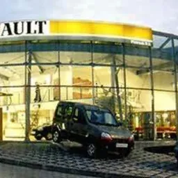 Nowoczesna fasada aluminiowo-szklana budynku z widocznymi roletami wewnętrznymi i elementami brukarstwa na zewnątrz.