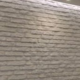 F.H.U.EURO-DOM - Ściana wykończona dekoracyjną okładziną imitującą kamień w odcieniach szarości i bieli, oświetlona od góry światłem punktowym i listwą LED, tworząca nowoczesny efekt wizualny.