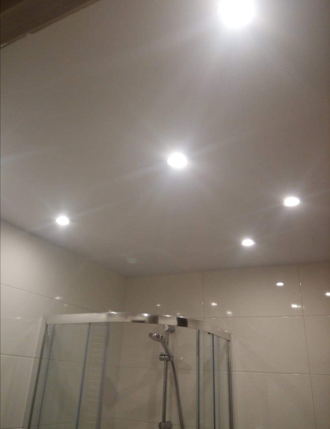 Biała łazienka z kabiną prysznicową i oświetleniem punktowym w suficie