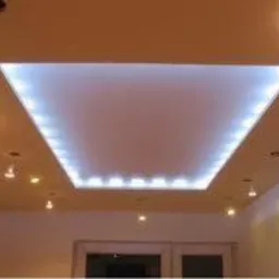 Podwieszany sufit z wbudowanym oświetleniem LED w kształcie trapezu, dodatkowe punkty świetlne na suficie i ścianach.