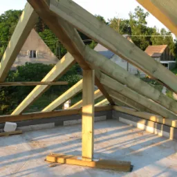 Konstrukcja drewniana dachu w trakcie budowy, widok z góry, zarys domów w tle. Elementy złączone śrubami, betonowa podstawa. Ujęcie z datą 29/06/2015.