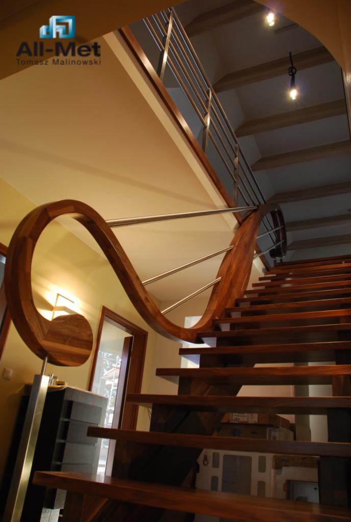 Drewniane schody z ozdobną, kręconą balustradą ze stali nierdzewnej, widok z dołu, logo firmy All-Met Tomasz Malinowski w lewym górnym rogu.