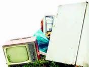 Stary telewizor kineskopowy, biała lodówka i inne sprzęty AGD składowane na trawie, przygotowane do wywozu.