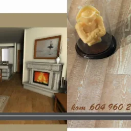 Wizualizacja salonu z kominkiem i elementami dekoracyjnymi: świeca w szklanym kloszu na drewnianej podłodze, salon z szarą sofą, drewnianym stolikiem kawowym, kominkiem z obrazem i kuchnią w tle.