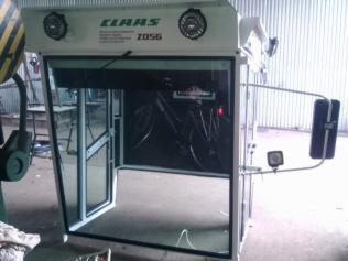 Kabina kombajnu Claas Z056 z otwartymi drzwiami, widoczna w warsztacie, z zamontowanym lusterkiem i oświetleniem.