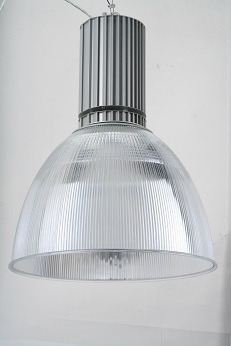 Lampa Highbay LED natynkowa z przezroczystym kloszem, zwieszona na lince, widoczna na białym tle. Obudowa lampy w kolorze srebrnym, żłobkowana.