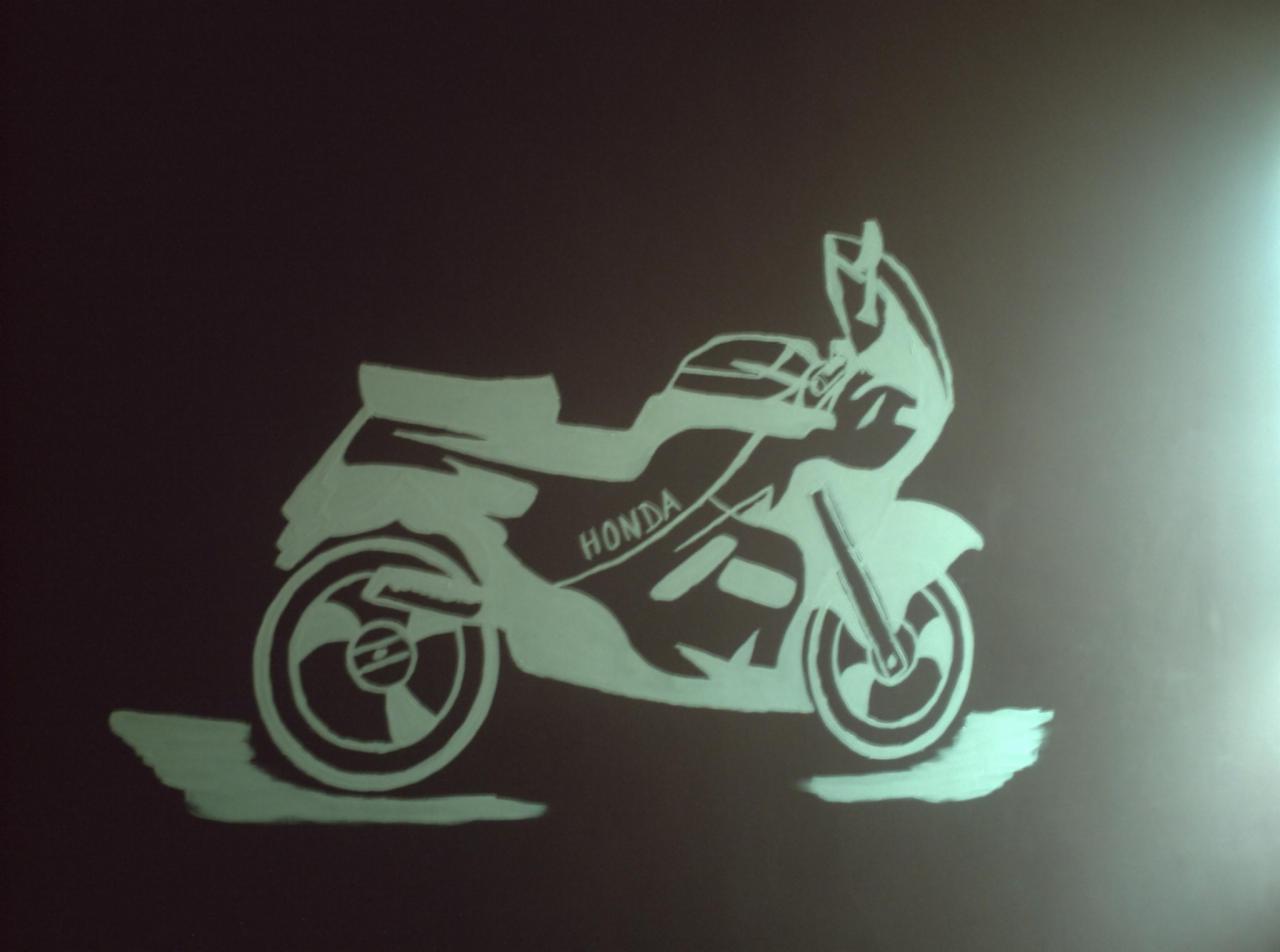 Artystyczny szablon motocykla Honda, wykonany farbą na ciemnej ścianie, z efektem świecenia.