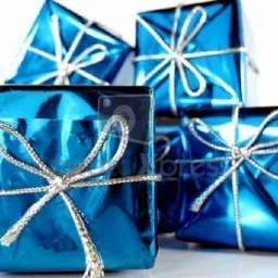 Cztery kwadratowe paczki prezentowe w błyszczącym, turkusowym papierze, owinięte srebrnym sznurkiem i przewiązane kokardą, ułożone na białym tle.