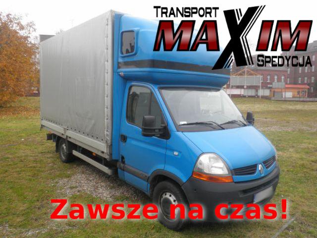 Niebieski samochód dostawczy Renault z plandeką i napisem 'TRANSPORT MAXIM SPEDYCJA' oraz hasłem 'Zawsze na czas!', zaparkowany na trawiastym terenie z budynkiem w tle.