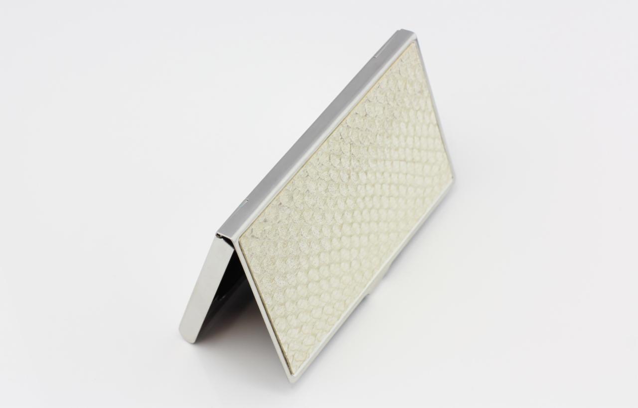 Otwarty, metalowy wizytownik z kremowym, teksturowanym wnętrzem przypominającym plaster miodu, ustawiony pod kątem na białym tle.