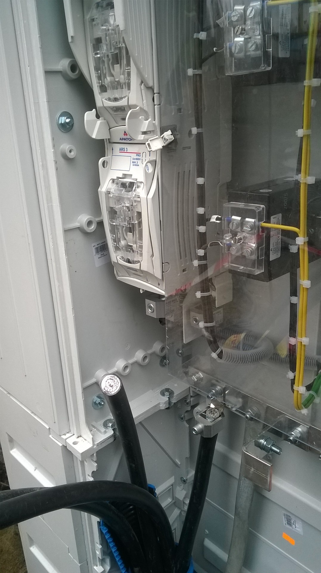 Wnętrze skrzynki elektrycznej z zabezpieczeniami, widoczne przewody, listwy zaciskowe i bezpieczniki firmy Apator ARS 3.