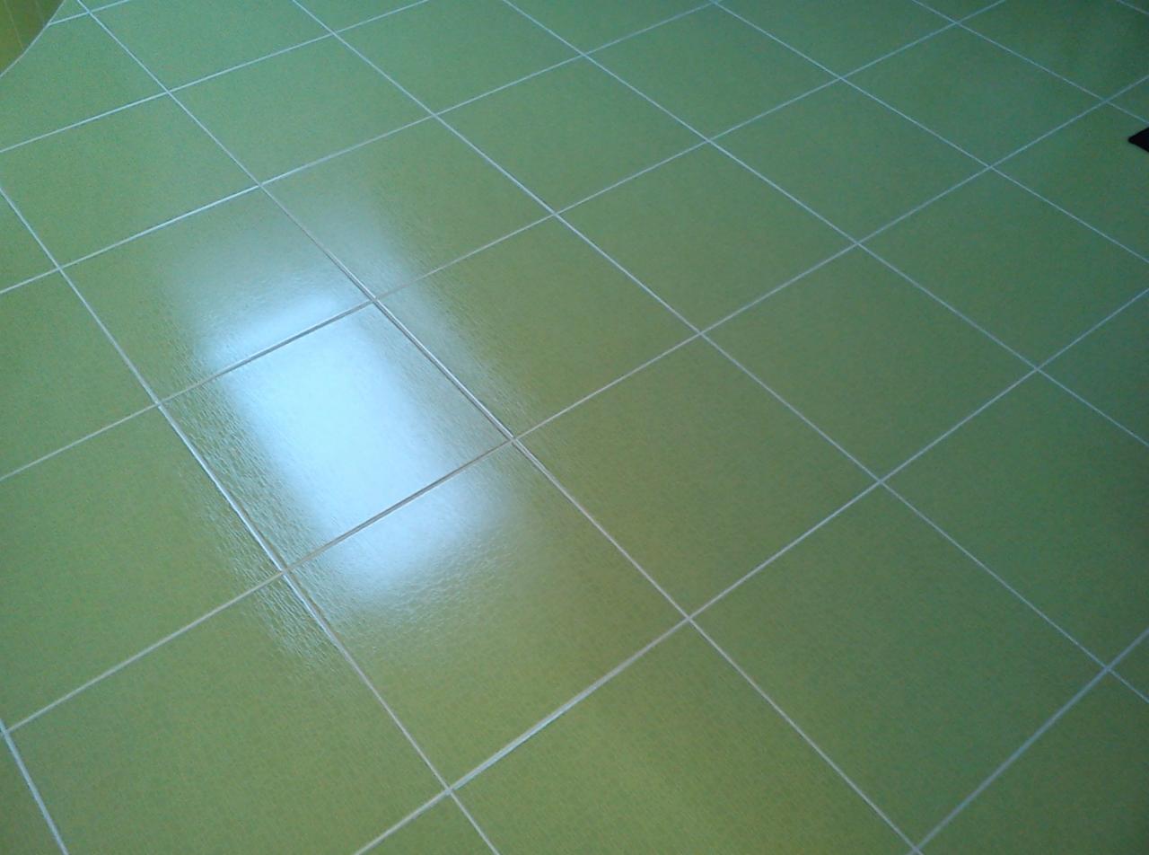 Świeżo położona, błyszcząca, jasnozielona terakota podłogowa z jasnymi fugami w łazience w Międzyborowie, odbijająca światło, widok z góry pod kątem.
